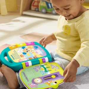 Imagem de criança pequena brincando com um livro de poemas e rimas interativo, com letras e números, enquanto está sentada em um tapete em ambiente interno.